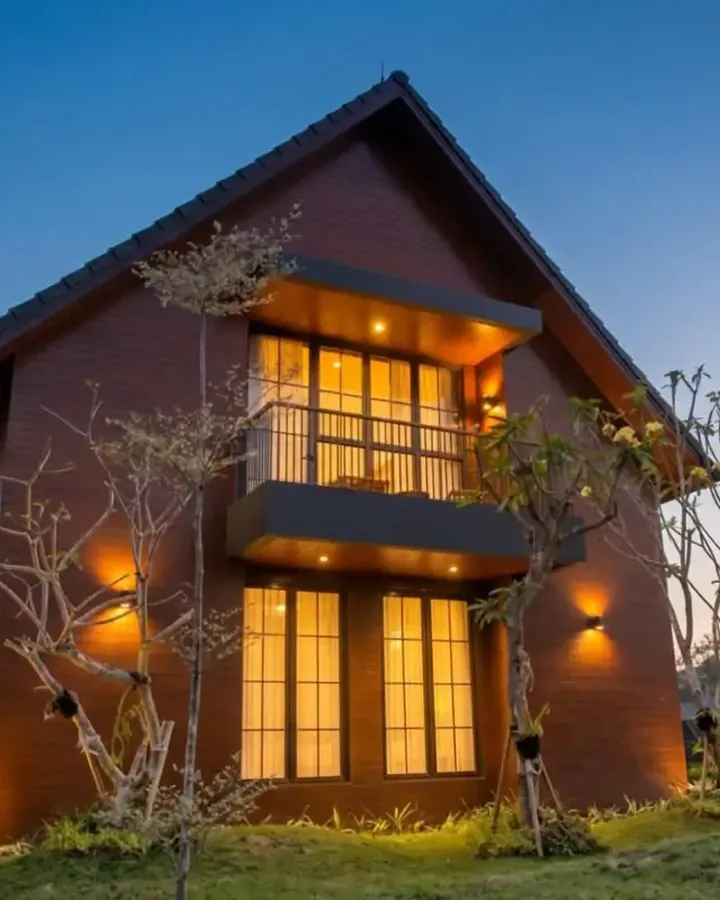 A modern brick house photographed at dusk with every window glowing
